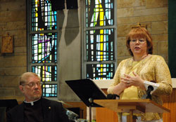 As the dean of the Terre Haute Deanery, Father Rick Ginther, left, listens during a July 14 press conference as Ann Ryan explains some of the changes that will result from a strategic plan to revitalize the Church in west central Indiana. Ryan is the communication chairperson of the Terre Haute Deanery Strategic Plan. (Photo by John Shaughnessy)