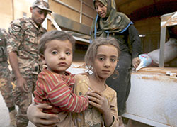 Syrian refugee children covered with dust arrive on Sept. 10 at the Jordanian border with Syria and Iraq, near the town of Ruwaished, which is close to Amman, Jordan. A Syrian family arrived in Indianapolis on Dec. 7. The husband, wife and two children fled their war-torn country three years ago due to the violence. (CNS photo/Muhammad Hamed, Reuters) 