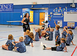 Youths of Holy Family Parish in New Albany raise their hands to answer a question posed by Totus Tuus catechist Jackie Parkes in the parish’s school gymnasium on June 19. (Photo by Natalie Hoefer)