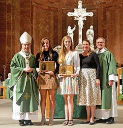 The recipients of this year’s archdiocesan Our Lady of Guadalupe Pro-Life Youth Award smile with their plaques of recognition: Margaret “Meggie” McPherson of St. Pius X Parish in Indianapolis, left, and Sally Jones of Immaculate Heart of Mary Parish in Indianapolis. They received the plaques from Archbishop Charles C. Thompson, archdiocesan Office of Human Life and Dignity coordinator Brie Anne Varick, and Deacon Michael Braun, archdiocesan Secretariat for Pastoral Ministries director, during the Respect Life Mass at SS. Peter and Paul Cathedral in Indianapolis on Oct. 6. (Photo by Natalie Hoefer)